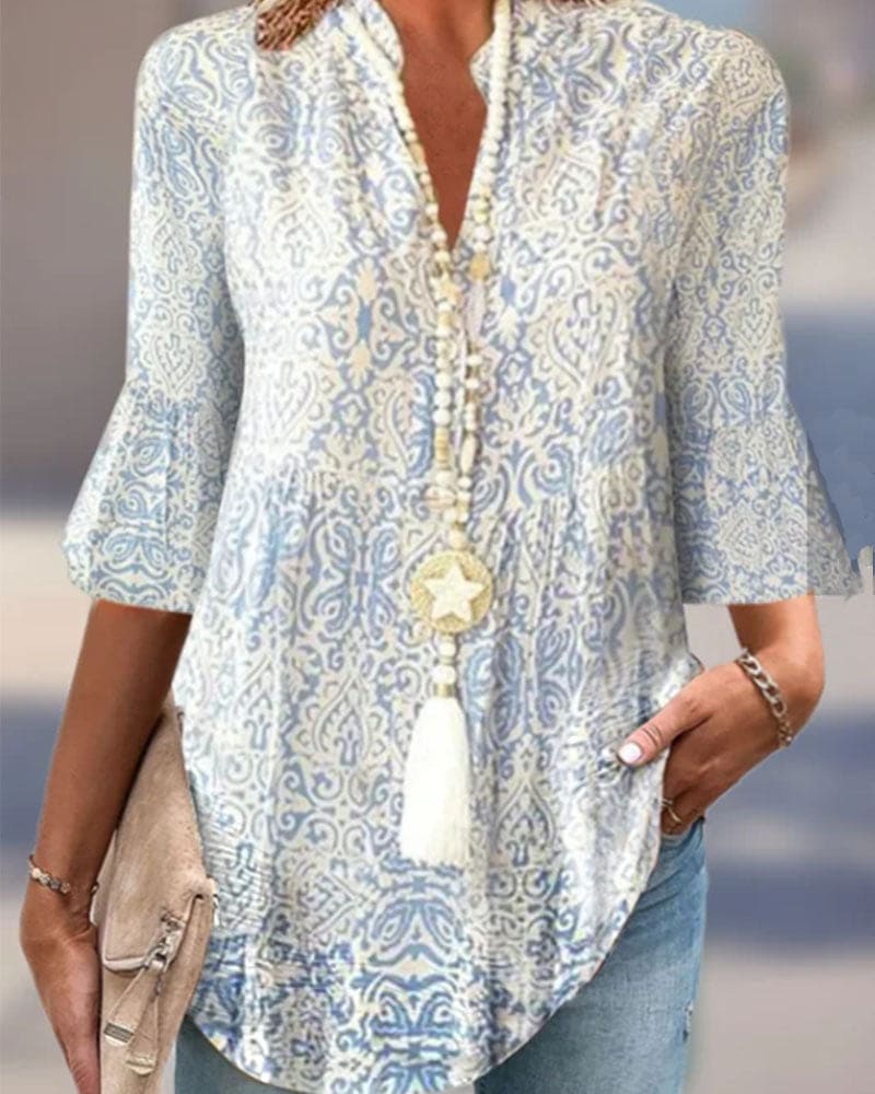 Kvinde iført lyseblå og hvid mønstret tunika med 3/4 ærmer og halskæde med stjernevedhæng. Casual mode, boheme stil, sommeroutfit.