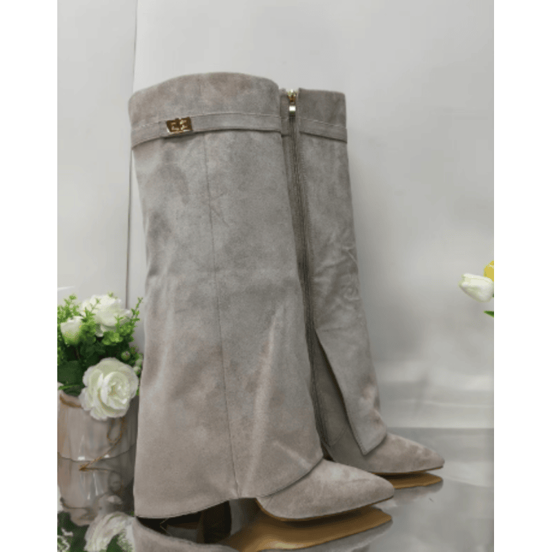 Grå ruskindsstøvler med høj hæl og lynlås, elegant design. Perfekt til modebevidste kvinder. Støvlerne står ved siden af hvide blomster.