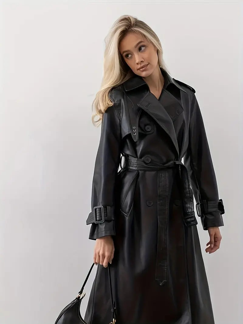 Blond kvinde iført sort læder trenchcoat med bælte, poserer mod hvid baggrund. Elegant mode, stilfuldt overtøj, moderne design.