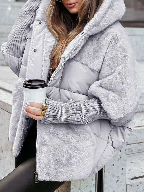 Kvinde iført grå, fluffy vinterjakke med hætte, holder en kaffekop. Perfekt til koldt vejr. Trendy vintermode, komfortabelt og stilfuldt look.