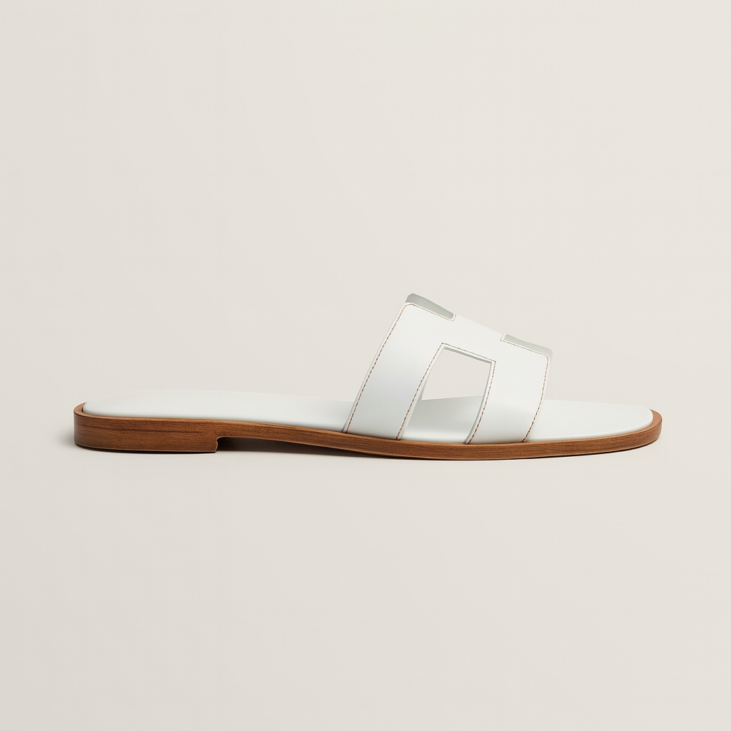 Hvid lædersandal med flad brun sål, minimalistisk design, perfekt til sommermode. Komfortabel og stilfuld fodtøj til kvinder.