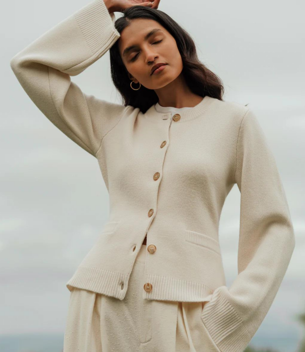Kvinde iført stilfuld, cremefarvet cardigan med knapper og vide ærmer. Perfekt til efterårsmode. Elegant og moderne look.