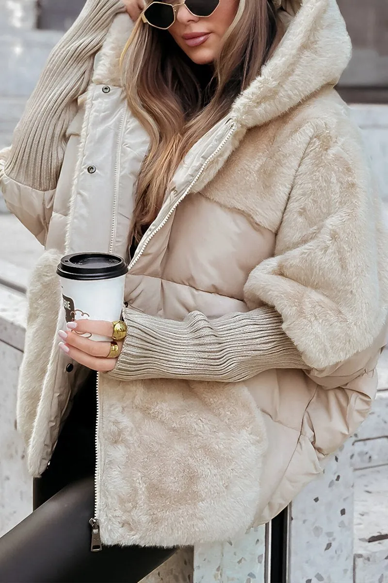 Kvinde iført beige plysjakke med hætte, holder en kaffekop. Mode, vintertøj, trendy jakke, street style, varm beklædning, udendørs.