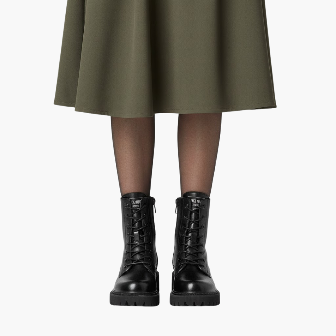 Sort læderstøvler med snørebånd på kvinde iført olivengrøn nederdel. Moderne fodtøj, stilfuldt design, perfekt til efterårsmode.