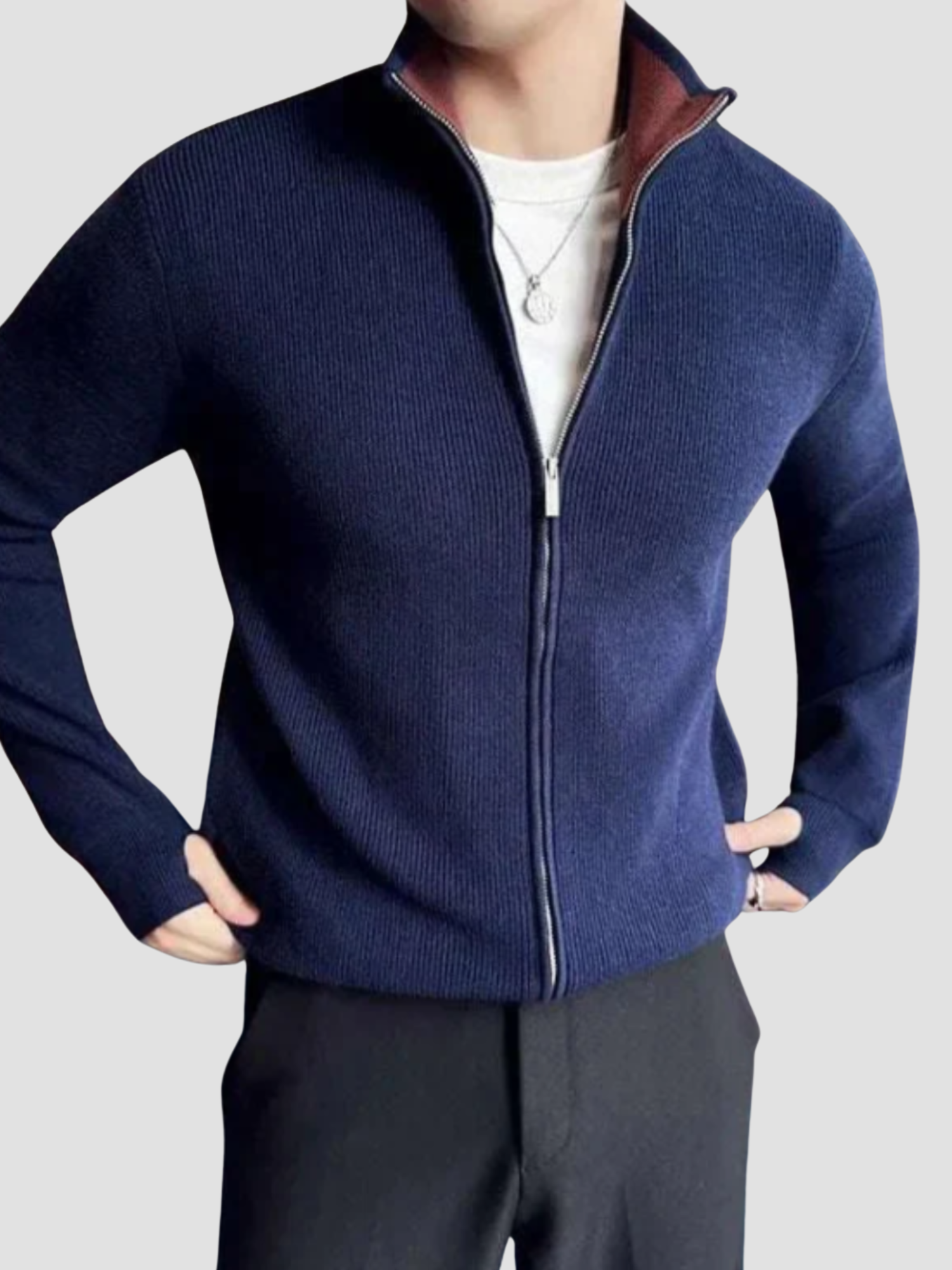 Mand iført mørkeblå striktrøje med lynlås, hvid t-shirt og sorte bukser. Moderne herremode, afslappet stil, vinterbeklædning.