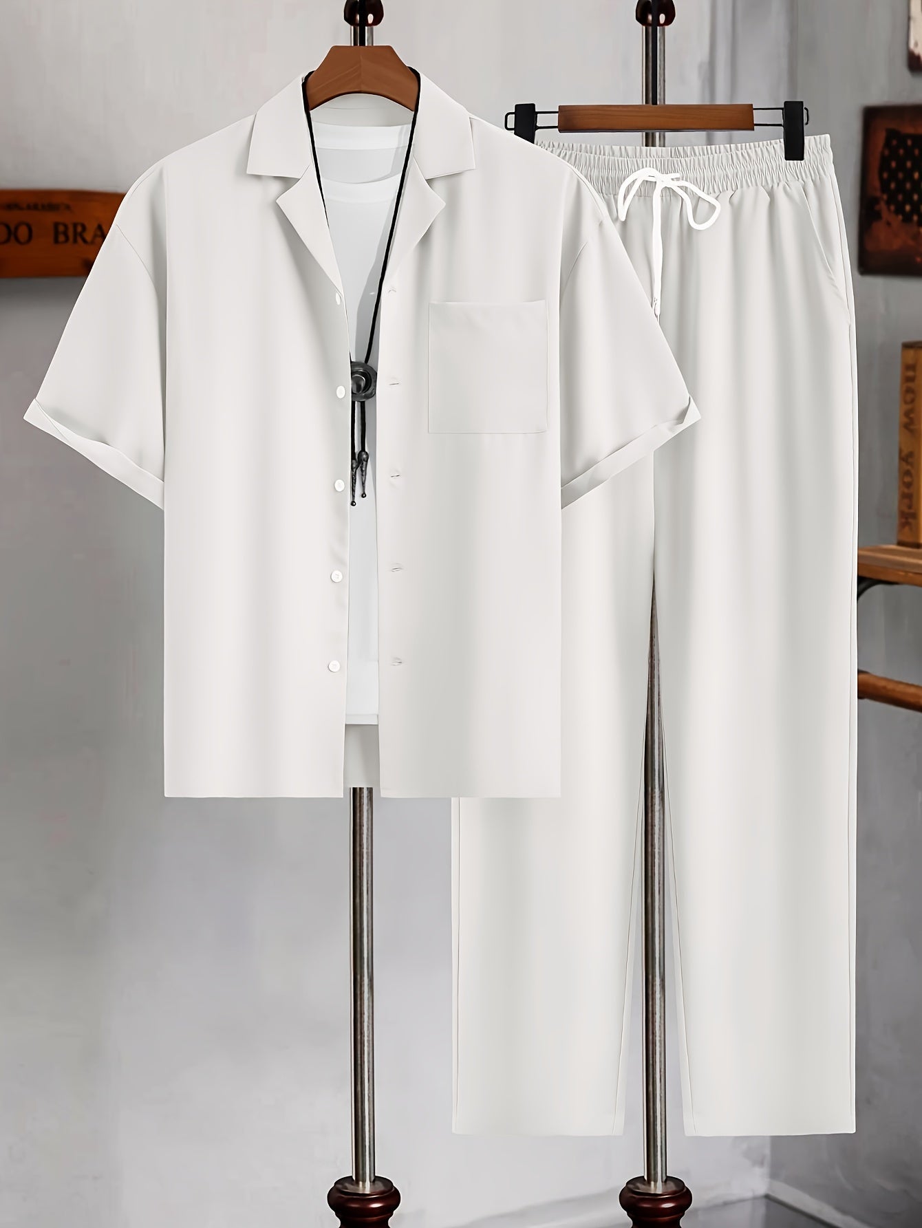 Kortærmet hvid skjorte og bukser sæt på bøjle i moderne minimalistisk stil. Perfekt til sommermode og afslappet herretøj.