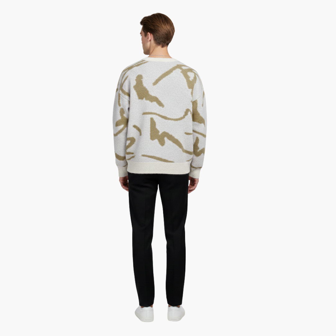 Mand i beige og hvid mønstret sweater, sorte bukser og hvide sneakers set bagfra. Moderne herremode, afslappet stil, minimalistisk design.