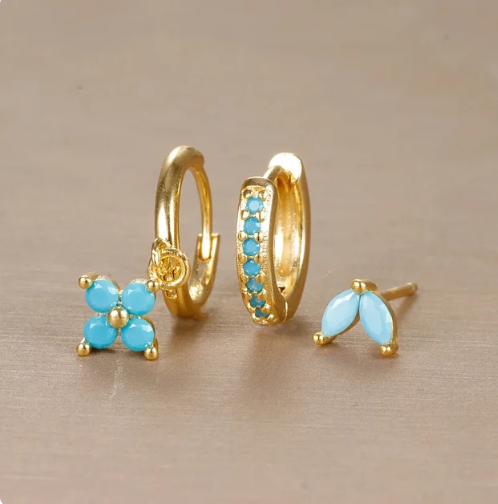 Guldøreringe med turkisblå sten, herunder en blomst, en ring med sten og en enkelt sten. Elegant smykkedesign til kvinder.