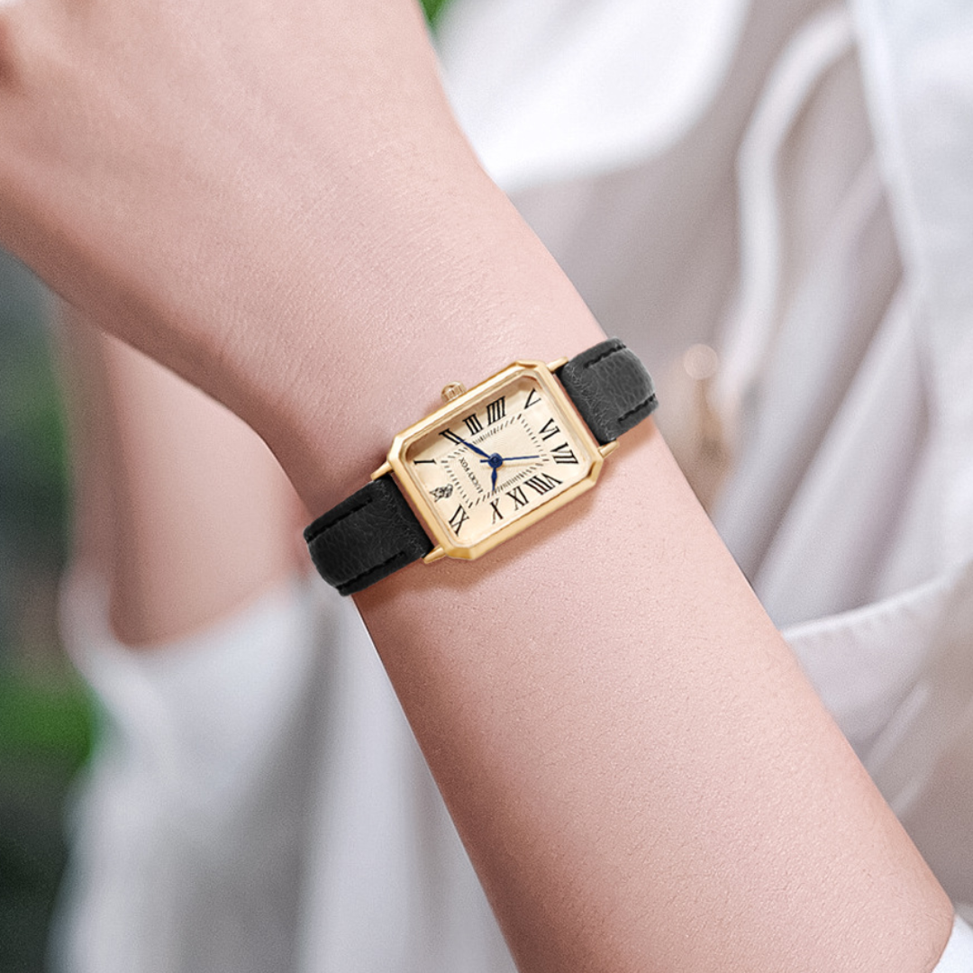 Sort læderrem ur med guld kvadratisk urkasse og romertal på urskiven, båret på håndled. Elegant og tidløst design til modebevidste.