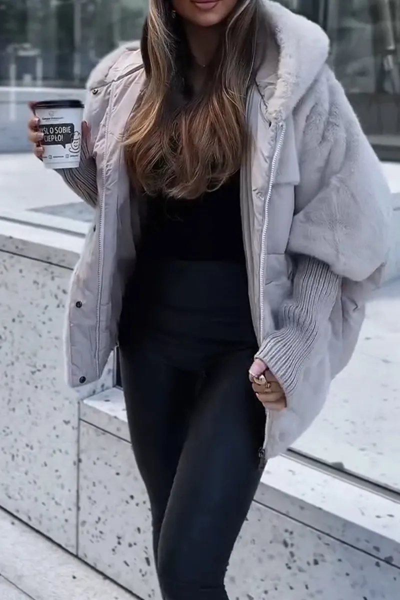 Kvinde iført grå pelsjakke og sorte læderbukser, holder en kaffekop. Mode, vintertøj, byliv, stilfuldt outfit, moderne kvindemode.