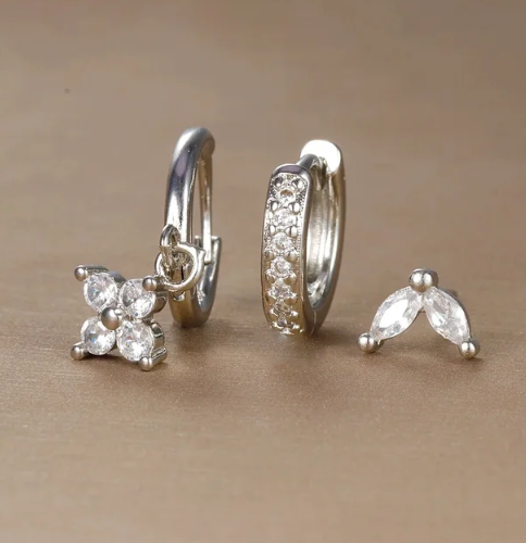 Sølv øreringe med klare krystaller, herunder en ring med vedhæng og en blomstret detalje. Elegant smykkedesign til kvinder.