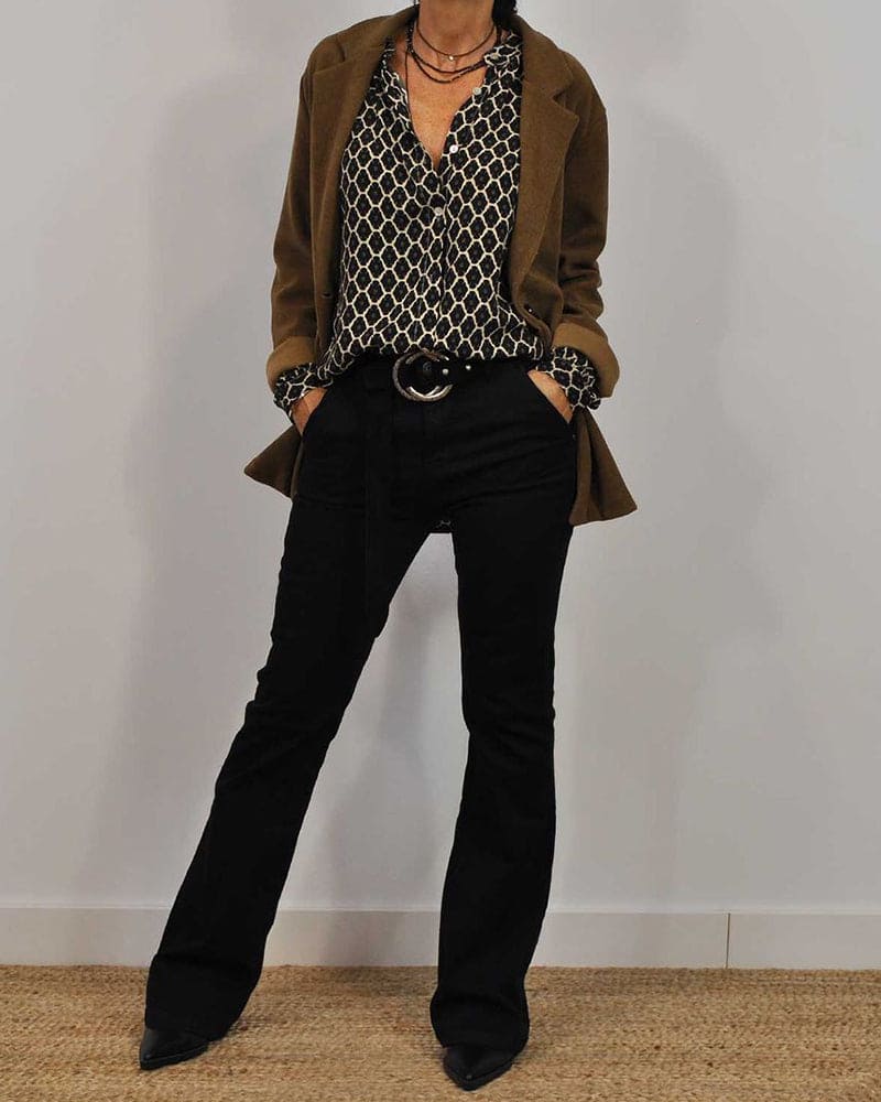 Kvinde iført brun blazer, mønstret skjorte og sorte bukser. Moderne efterårsoutfit, stilfuldt og elegant tøj til kvinder. Modeinspiration.