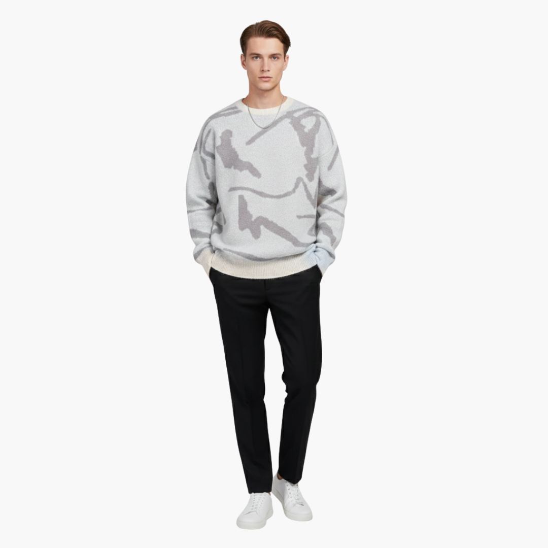 Ung mand iført grå camouflagemønstret sweater, sorte bukser og hvide sneakers. Moderne herremode, afslappet stil, minimalistisk look.