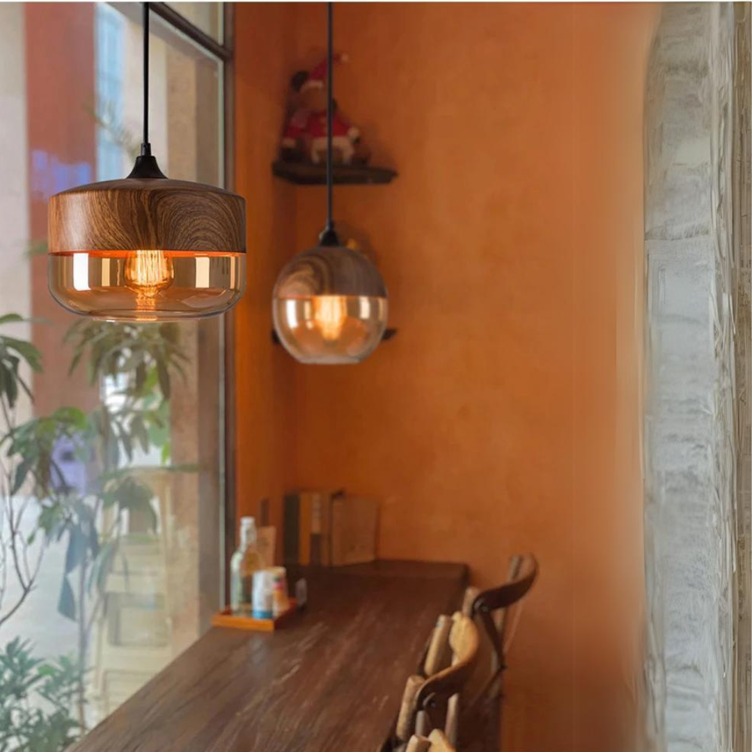 Hængelampe i træ og glas over træbord i hyggelig café med orange vægge. Moderne belysning, indretning, caféstemning, skandinavisk design.