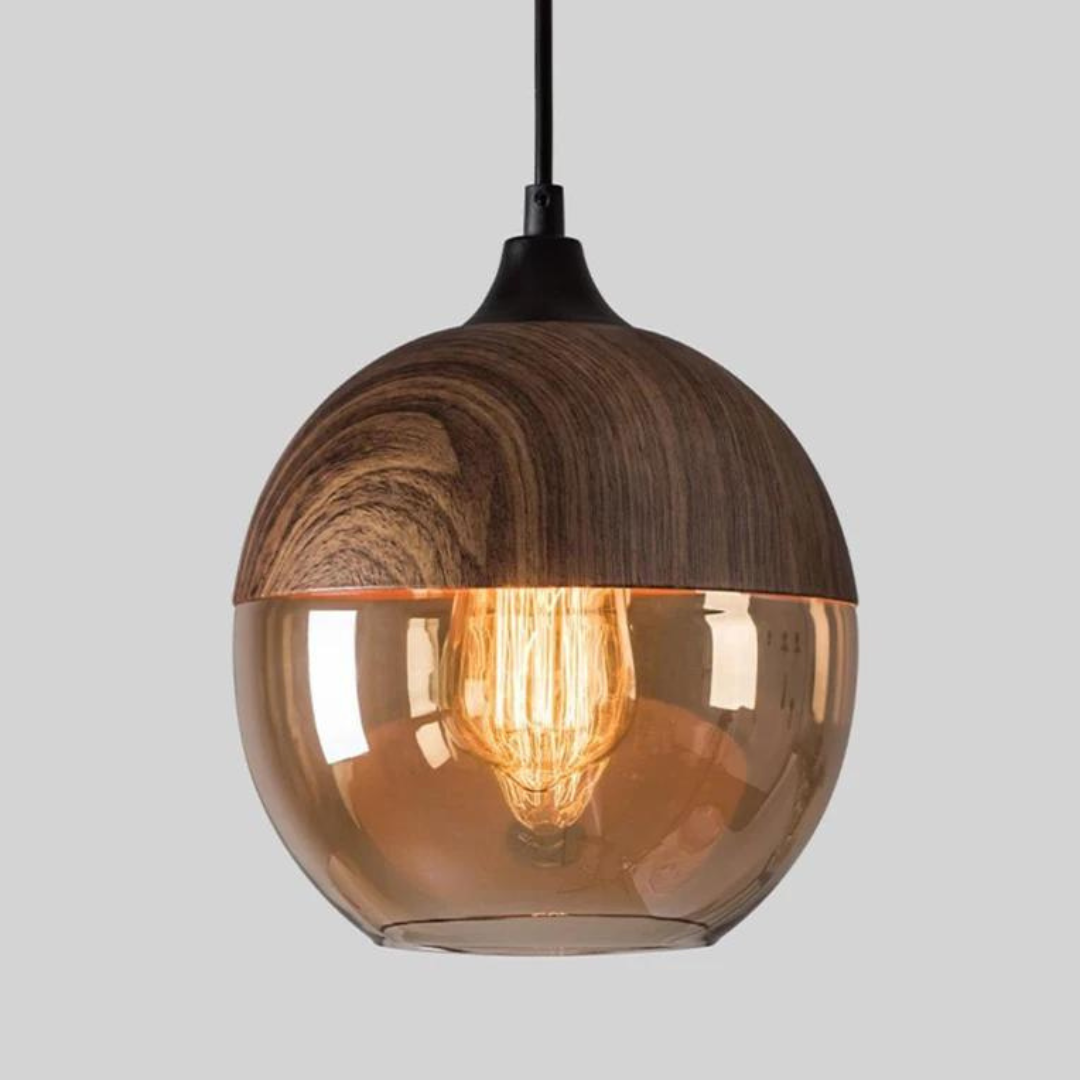 Moderne pendellampe i træ og glas med synlig glødepære, hængende fra sort ledning. Stilfuldt design til indretning og belysning.