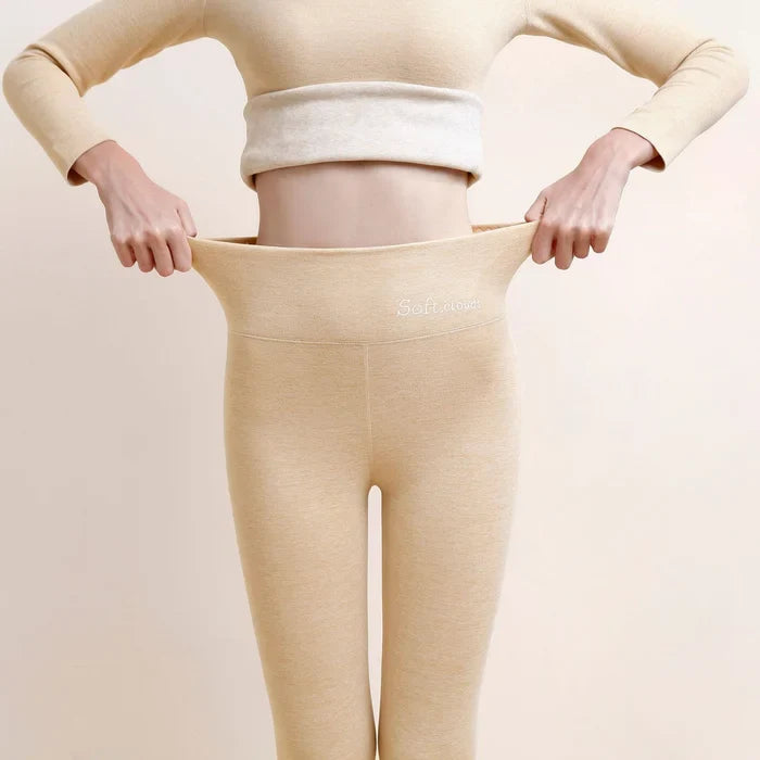 Kvinde iført beige termoundertøj, der viser elastisk talje. Komfortabelt, varmt tøj til vinter. Ideelt til kolde temperaturer og udendørs aktiviteter.