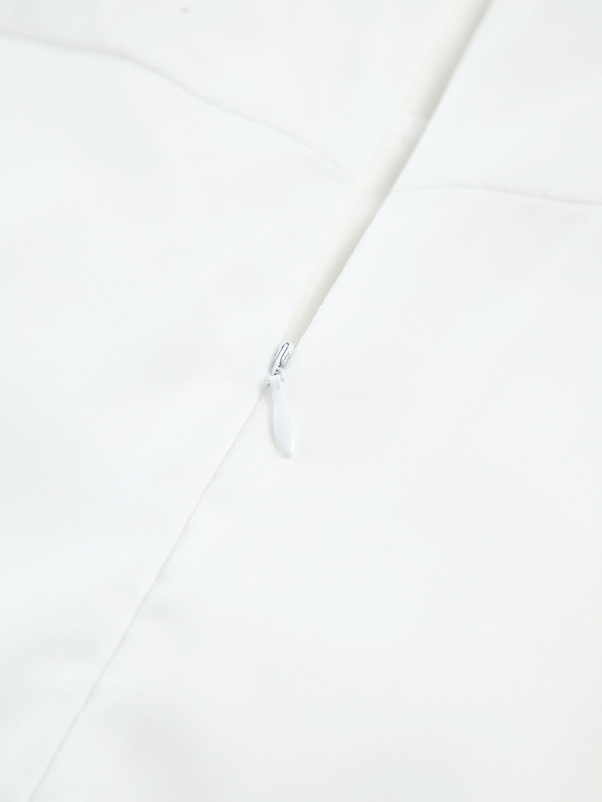 Hvid lynlås på glat stof, nærbillede. Minimalistisk design, mode, tekstil, tøjdetalje. Perfekt til moderne beklædning og skræddersyede kjoler.