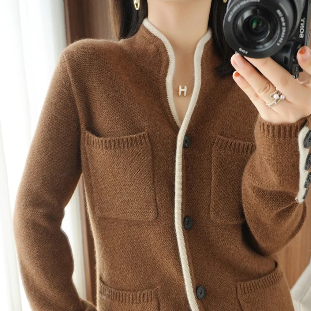 Brun cardigan med lommer og hvide kanter, bæres af kvinde med kamera. Striktrøje mode, efterårstøj, stilfuldt design, komfortabelt look.