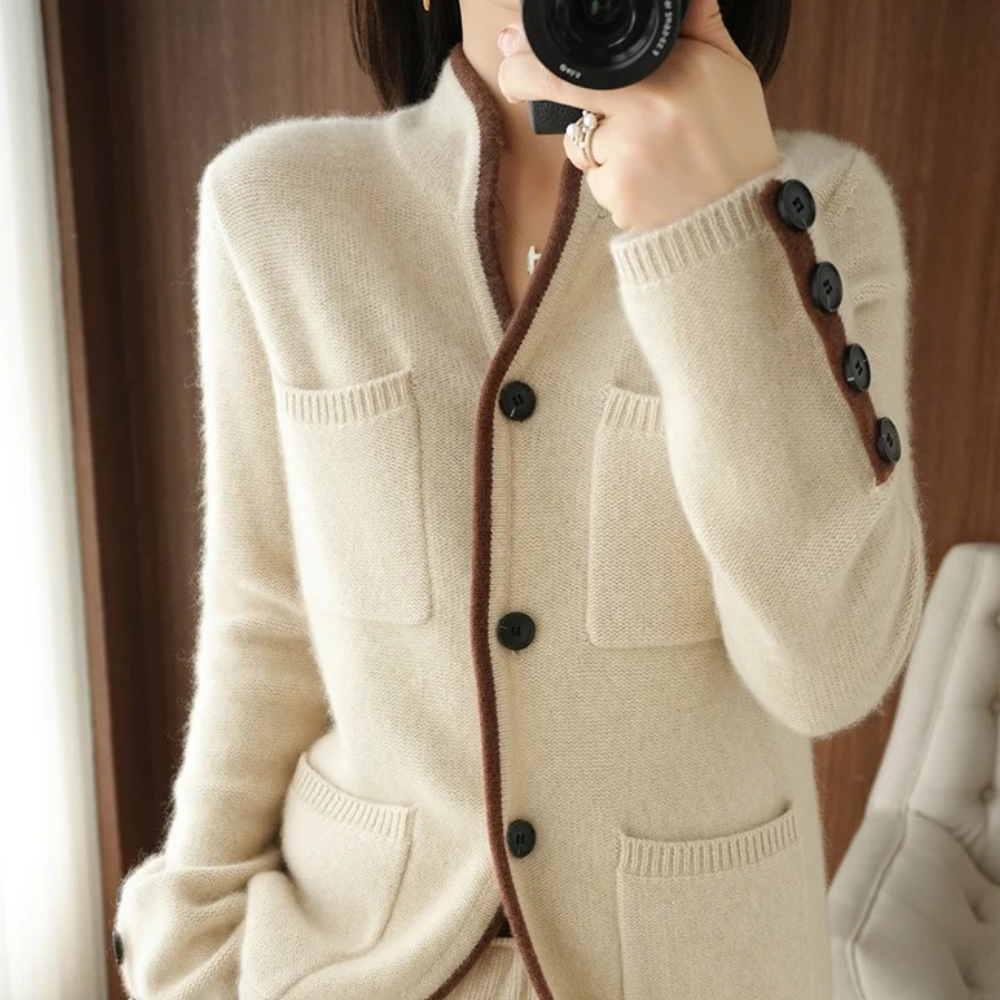 Beige cardigan med sorte knapper og lommer, elegant design, kvinde fotograferer sig selv, moderne mode, stilfuldt tøj, indendørs.