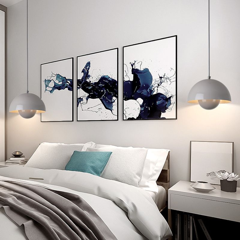 Moderne soveværelse med hvid seng, grå sengetæppe, blå pude, abstrakte kunstværker på væggen og to hængelamper. Skandinavisk indretning.