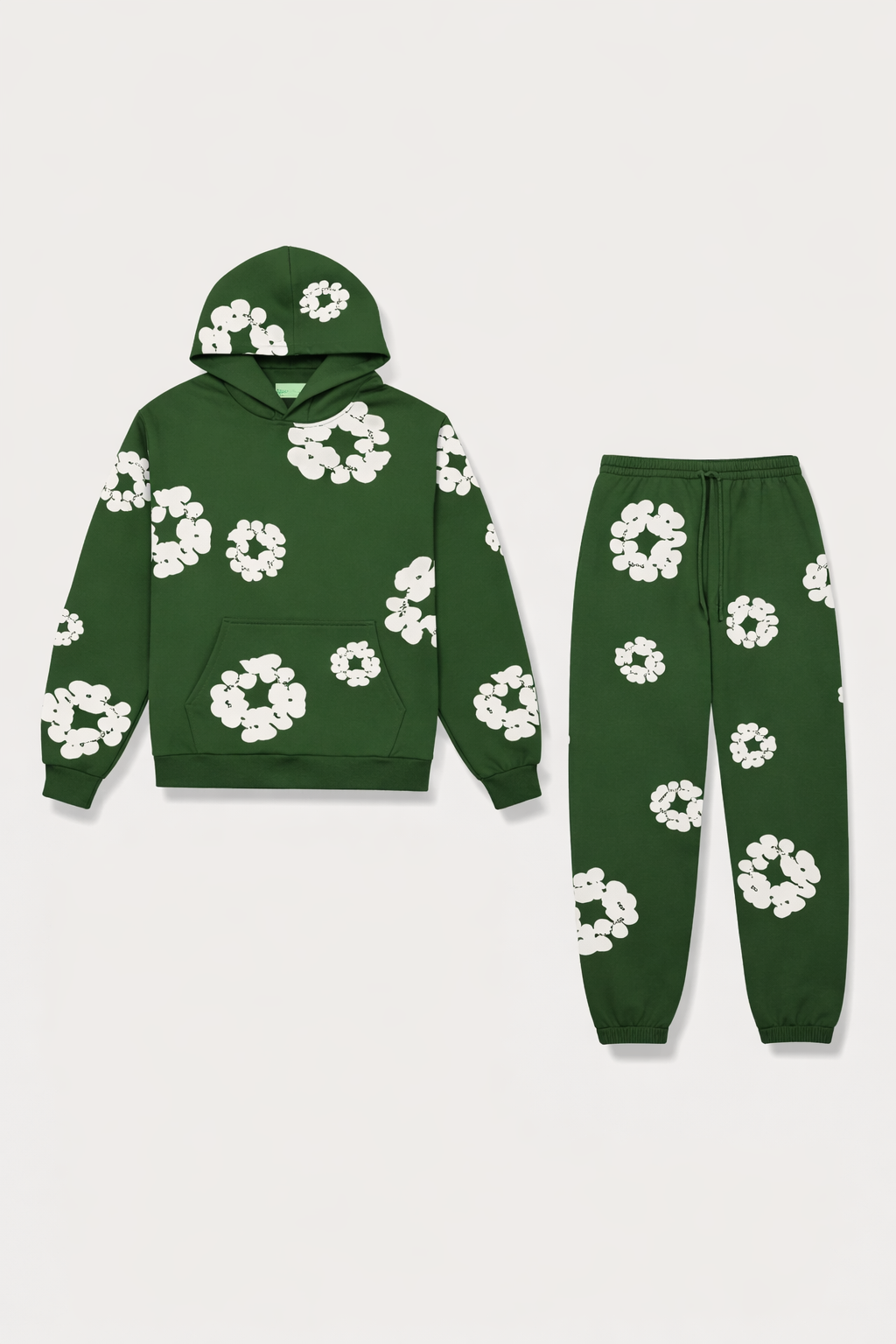 Grønt joggingsæt med hættetrøje og bukser, dekoreret med hvide blomstermotiver. Komfortabelt og stilfuldt tøj til afslapning og fritid.