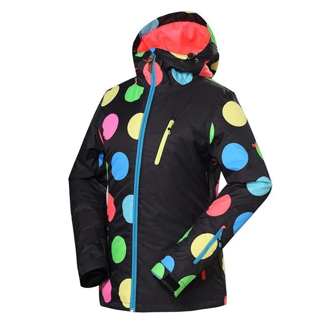 Farverig vinterjakke med store polkaprikker, hætte og lynlås. Ideel til skiferie og udendørsaktiviteter. Trendy og funktionel beklædning.