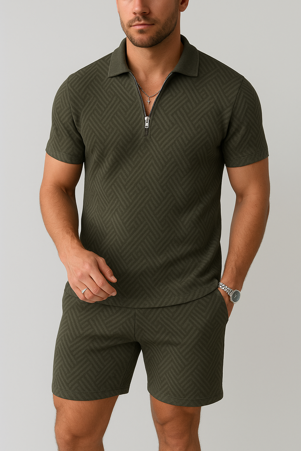 Mand iført olivengrøn poloshortsæt med lynlåsdetalje og geometrisk mønster. Moderne herremode, sommeroutfit, stilfuldt tøj.