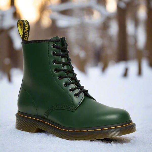 Grøn Dr. Martens støvle i sneklædt skov, ikonisk design, læder, gule syninger, vintermode, robust fodtøj, udendørs stil.