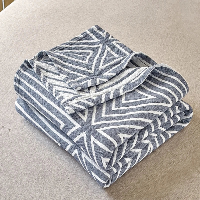 Gråt og hvidt geometrisk mønstret tæppe på beige baggrund. Blødt bomuldstæppe, moderne design, hjemmetilbehør, indretning.