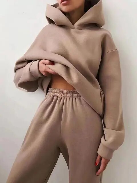Kvinde iført beige hættetrøje og joggingbukser, afslappet mode, komfortabelt tøj, minimalistisk stil, moderne streetwear, casual look.