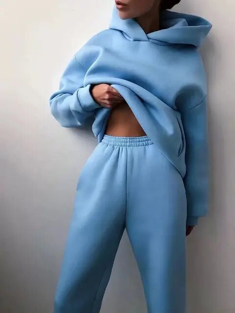 Kvinde iført lyseblå hættetrøje og joggingbukser, afslappet tøjstil, komfortabelt loungewear, moderne mode, minimalistisk design.