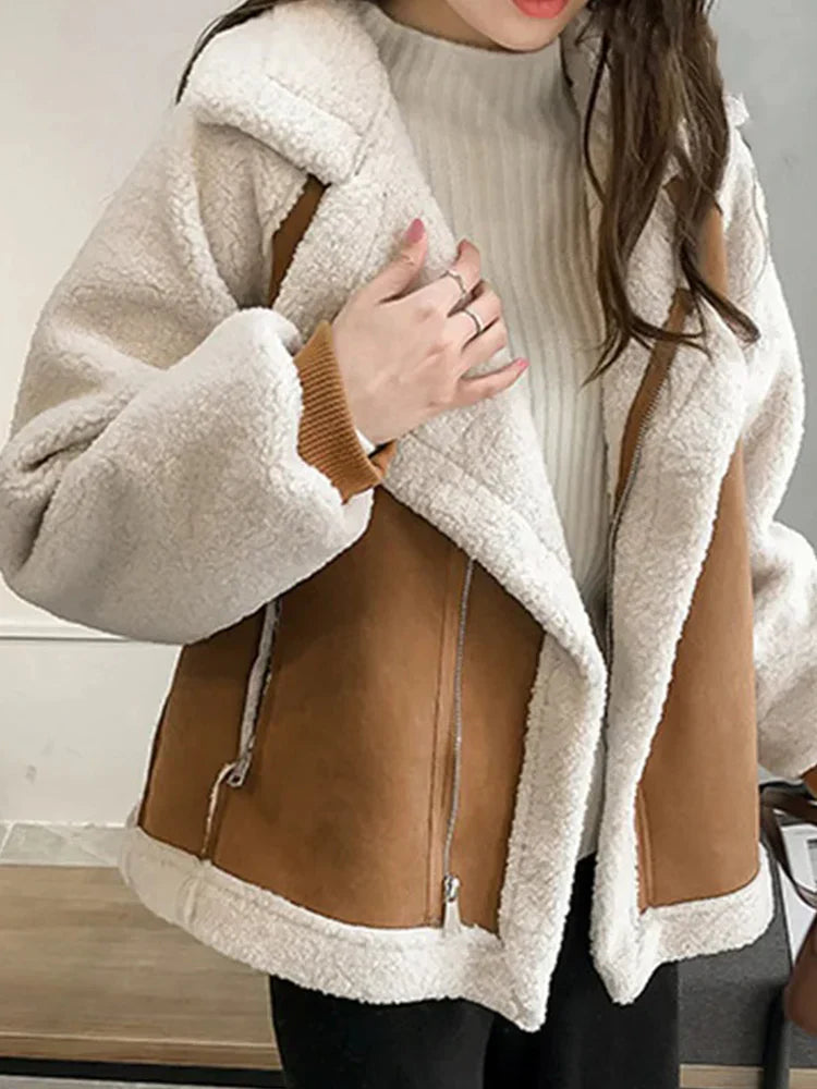 Kvinde iført trendy, varm teddyjakke med hvidt plys og brune detaljer. Perfekt til vintermode og stilfuldt vintertøj.