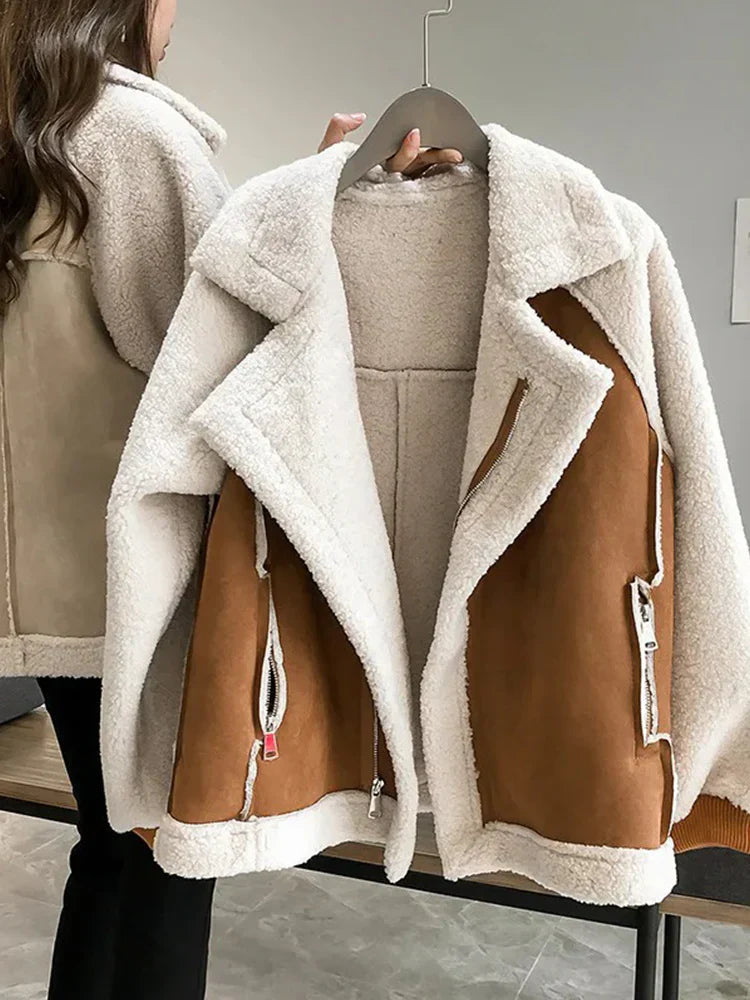 Damejakke i hvidt og brunt teddyfleece, hængende på bøjle. Varm vinterjakke, trendy overtøj, blød pelsjakke til kvinder.