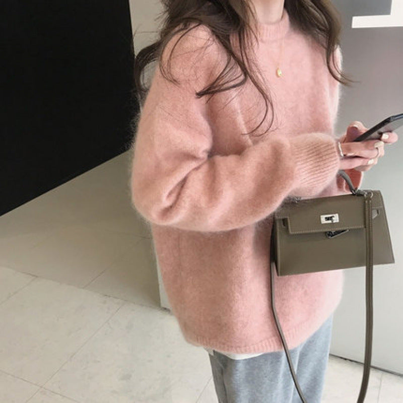 Kvinde i lyserød sweater holder smartphone og bærer en lille, grå håndtaske. Moderne mode, casual stil, trendy accessories.