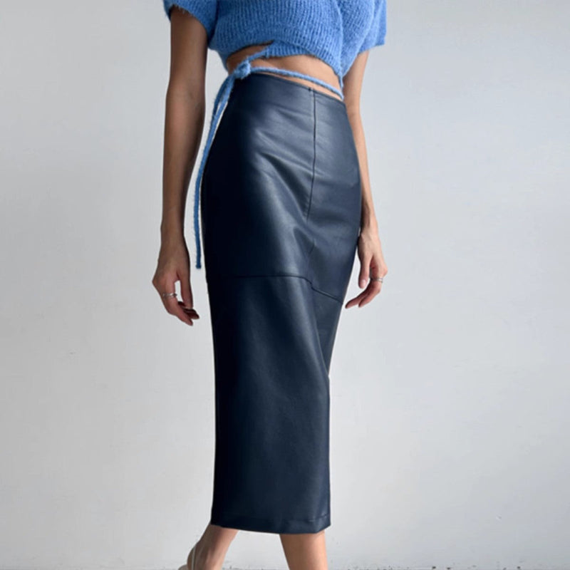 Kvinde iført blå crop top og sort læder nederdel. Moderne mode, minimalistisk stil, trendy outfit, elegant tøj til kvinder, stilfuldt look.