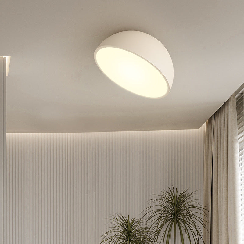 Moderne hvid loftlampe i minimalistisk design, der lyser et stilfuldt rum op med neutrale farver og indendørs planter.
