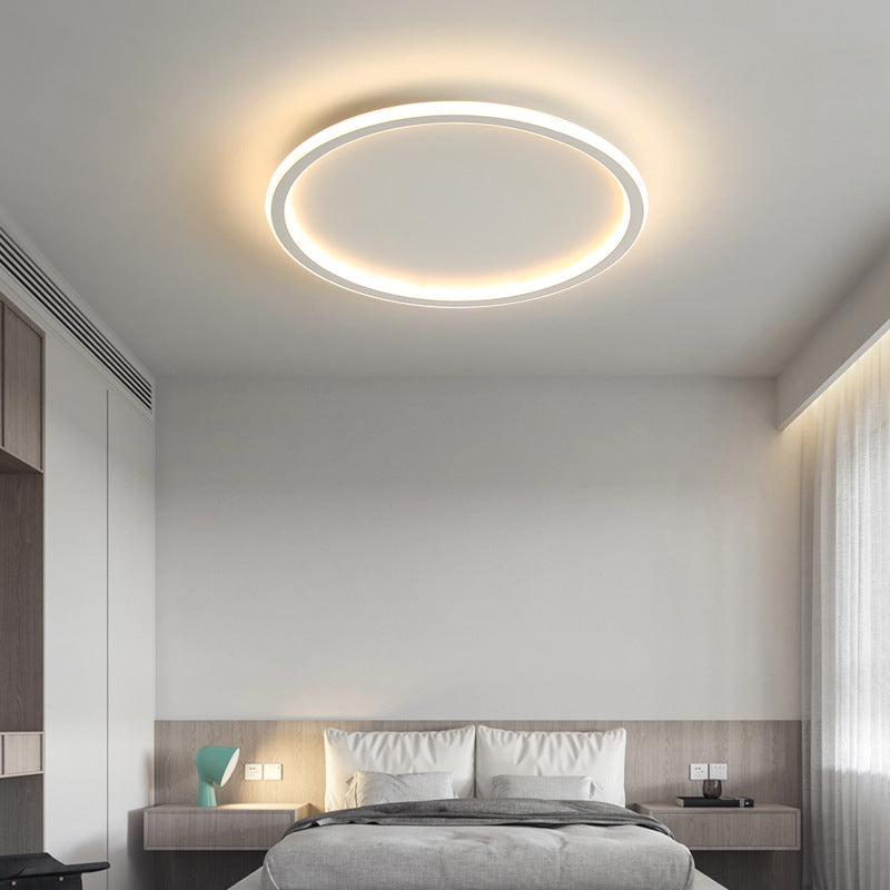 Moderne soveværelse med rund LED-loftlampe, minimalistisk indretning, grå sengetøj og træmøbler. Energi-effektiv belysning, stilfuldt design.