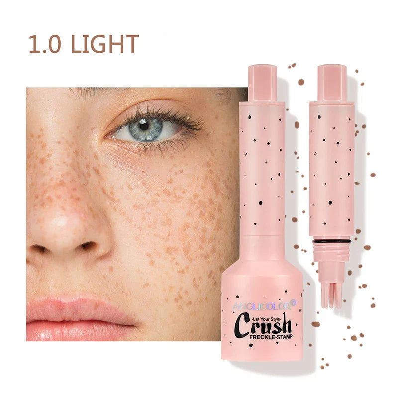 Nærbillede af kvindes ansigt med fregner, ved siden af en lyserød freklenstempel makeup-produkt, mærket "Anglicolor", farve 1.0 Light.