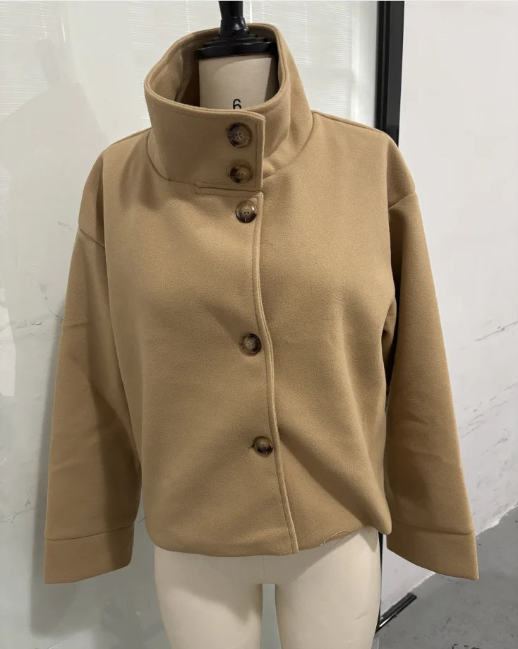 Beige uldjakke med høj krave og knaplukning på mannequin. Stilfuld og moderne design, perfekt til efterårsmode.
