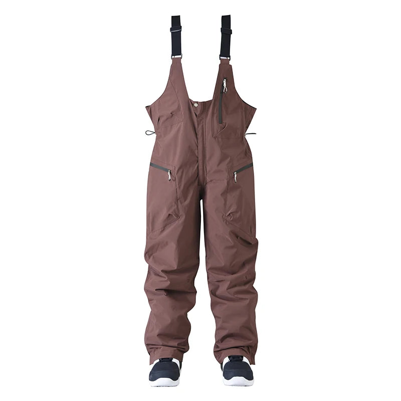 Brune skibukser med seler, lynlåslommer og justerbare stropper. Ideelle til vinteraktiviteter. Vandtæt og åndbar beklædning til ski og snowboard.