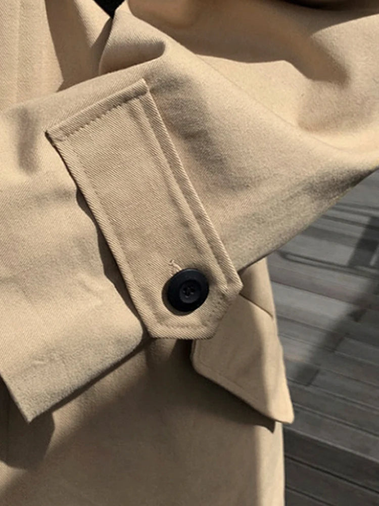 Beige trenchcoat med sort knapdetalje på ærmet, elegant design, moderigtigt overtøj, klassisk stil, perfekt til forår og efterår.