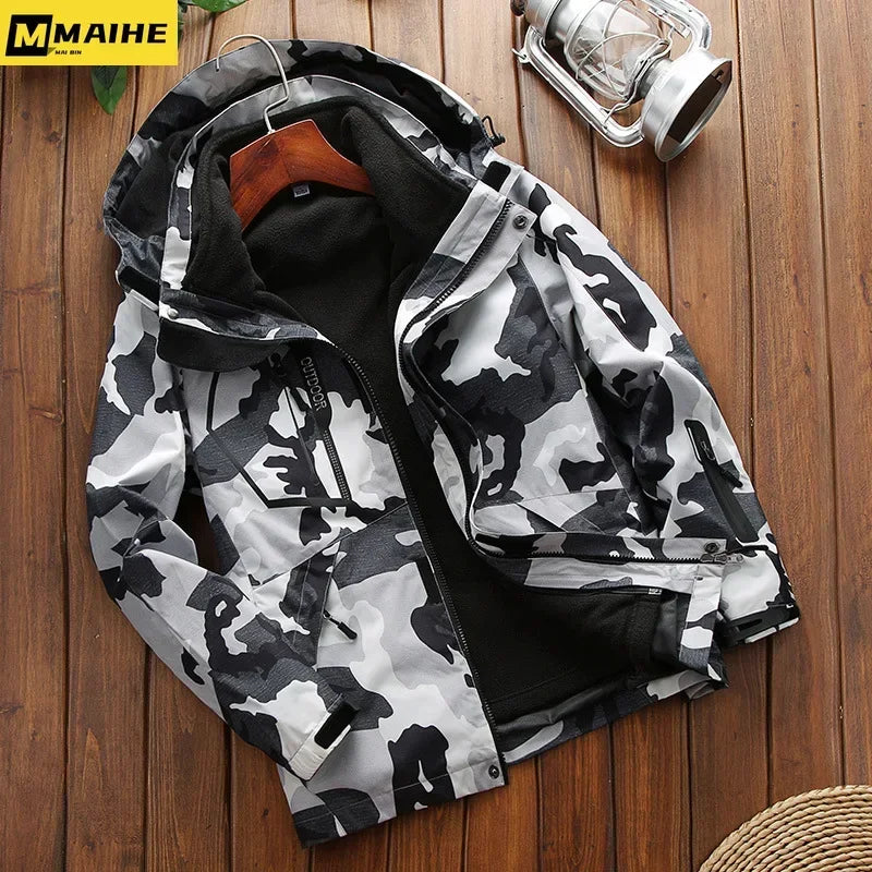 Grå og sort camouflagejakke med hætte på træbord, ved siden af en lanterne. Vinterjakke til mænd, udendørs tøj, stilfuldt design.