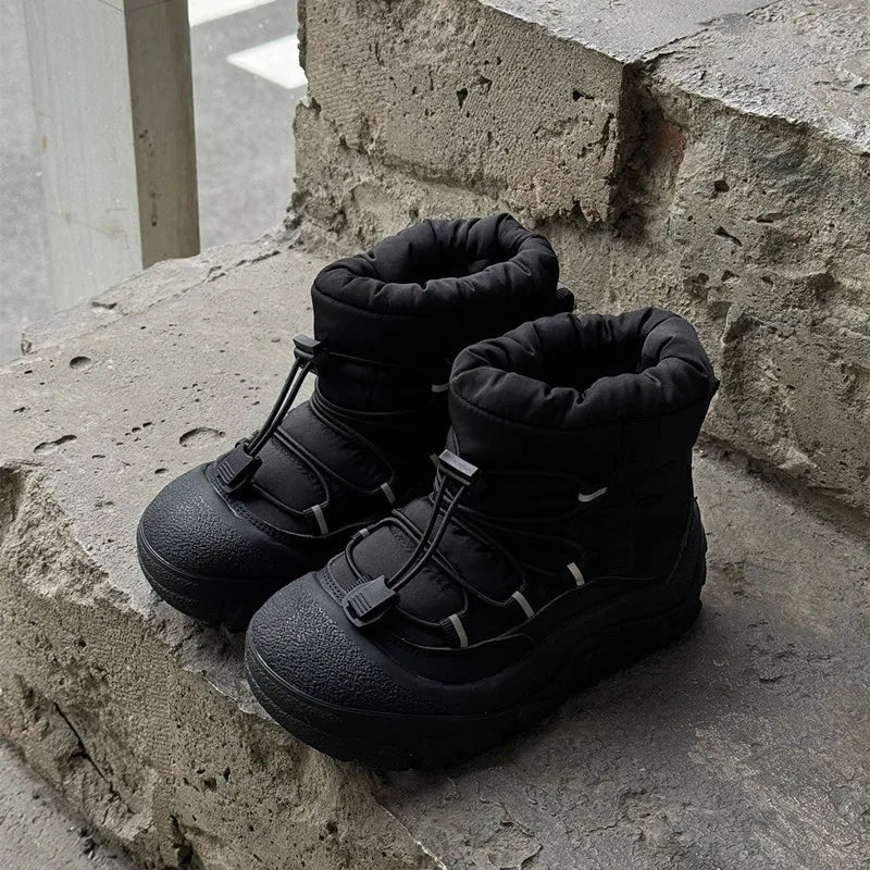 Sort vinterstøvler med snørebånd på betontrappe. Vandtætte og isolerede støvler til koldt vejr. Perfekte til udendørs aktiviteter om vinteren.