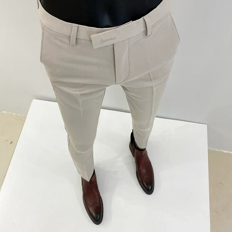 Beige herrebukser på mannequin med brune læderstøvler, moderne herremode, stilfuldt tøj, elegant design, perfekt til formelle anledninger.