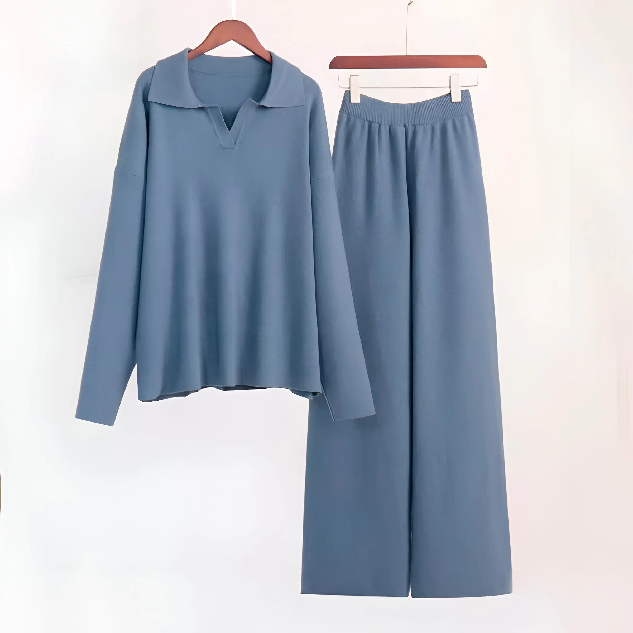 Blåt sæt tøj med langærmet trøje og vide bukser på bøjler. Moderne, minimalistisk design, perfekt til casual og stilfulde outfits.