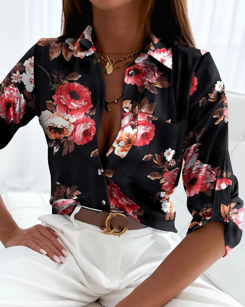 Kvinde iført sort bluse med røde blomster, dyb V-udskæring og hvide bukser. Trendy mode, elegant stil, blomsterprint, moderne tøj.