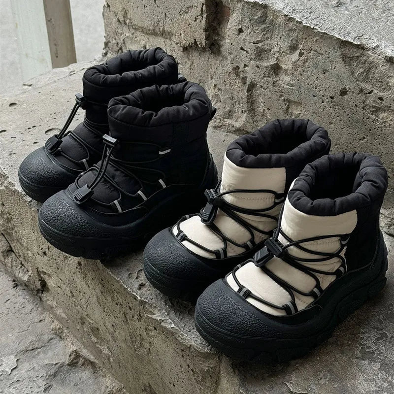 To par vinterstøvler i sort og hvid på betontrappe. Vandtætte, isolerede støvler med snørebånd, ideelle til kolde vejrforhold.