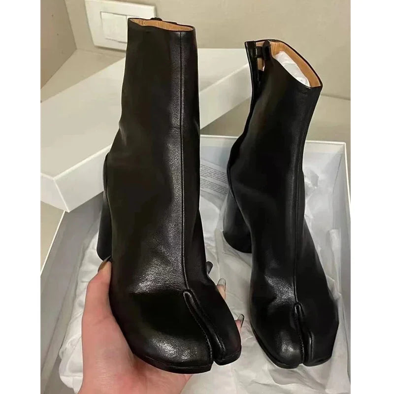 Sorte Tabi-støvler i læder med delt tå, præsenteret i en åben skotøjsæske. Moderne design, populært fodtøj, unikt look.