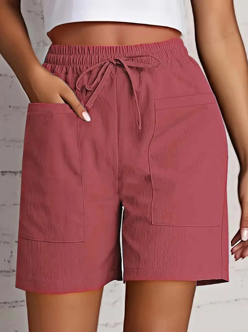 Kvinde iført lyserøde shorts med elastisk talje og snøre, store forlommer. Perfekt til sommermode og afslappet stil.