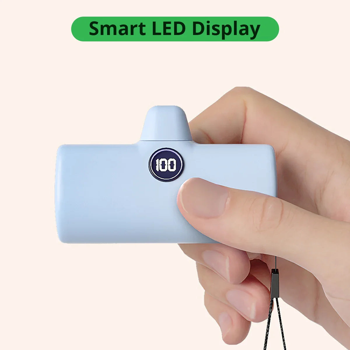 Hånd holder en blå bærbar oplader med smart LED-display, der viser batteriniveau. Kompakt powerbank, ideel til rejser og daglig brug.